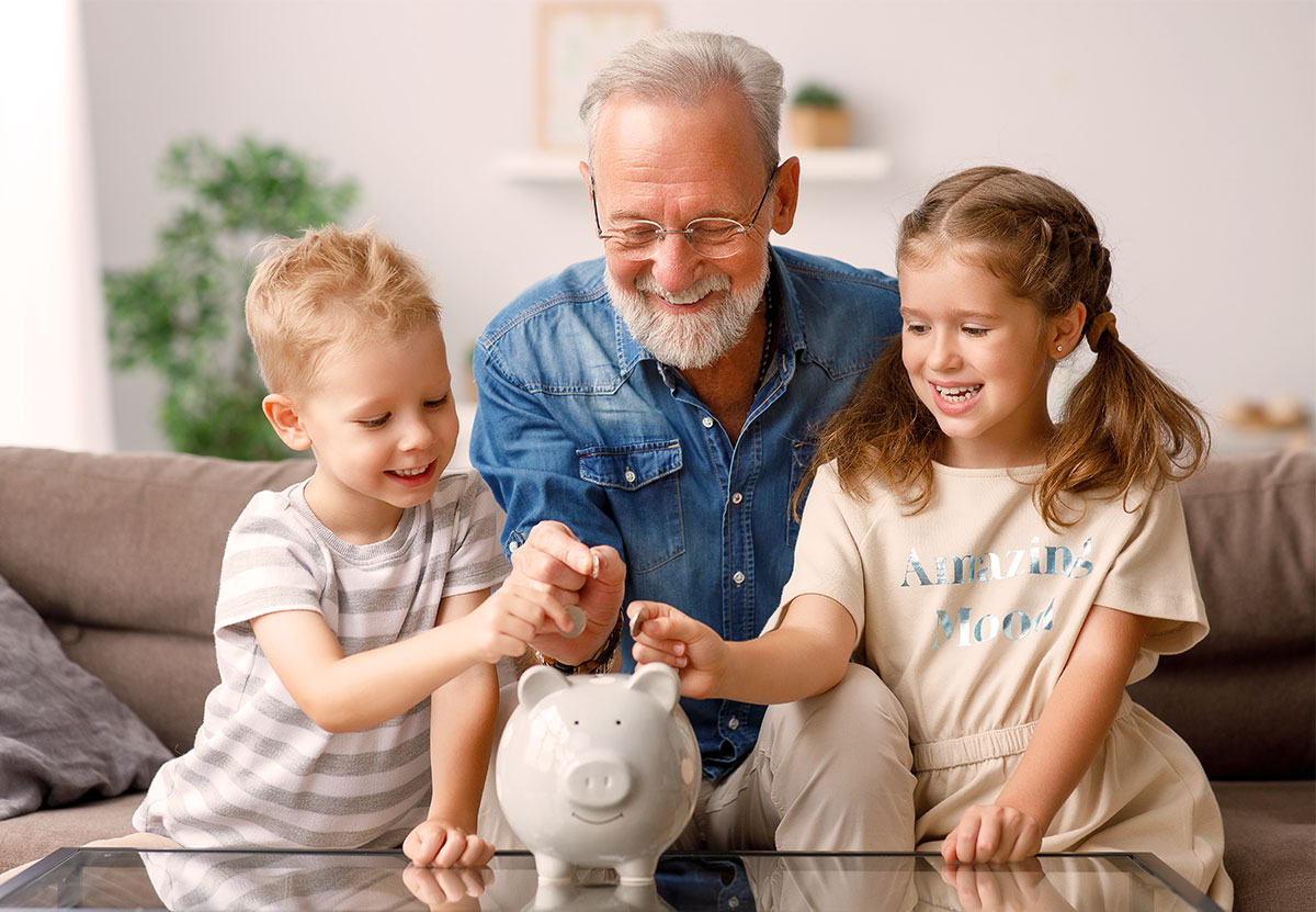 grandfather with children adding coins to piggy bank